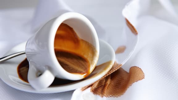 En kaffekopp velter og lager en flekk.