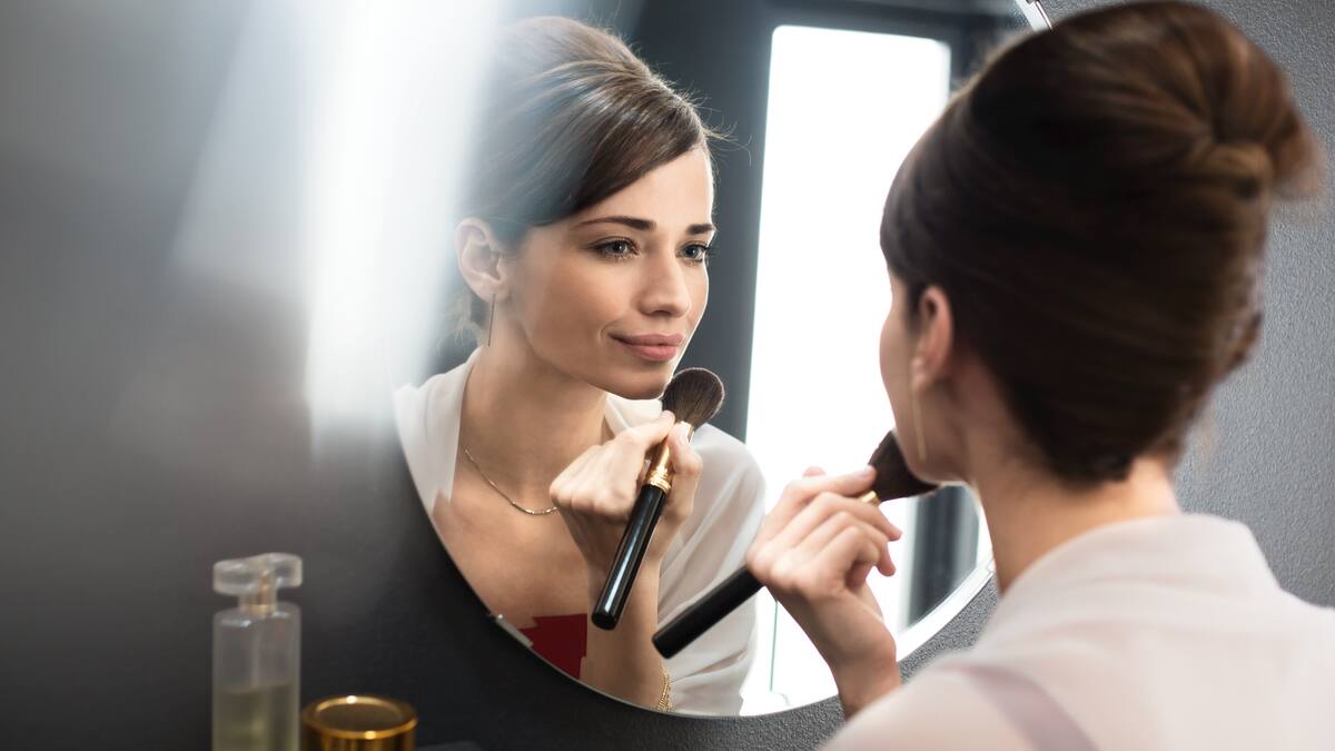 Una donna applica il make-up davanti allo specchio