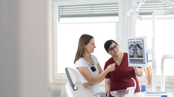 A dentist and her assistant look at an X-ray image