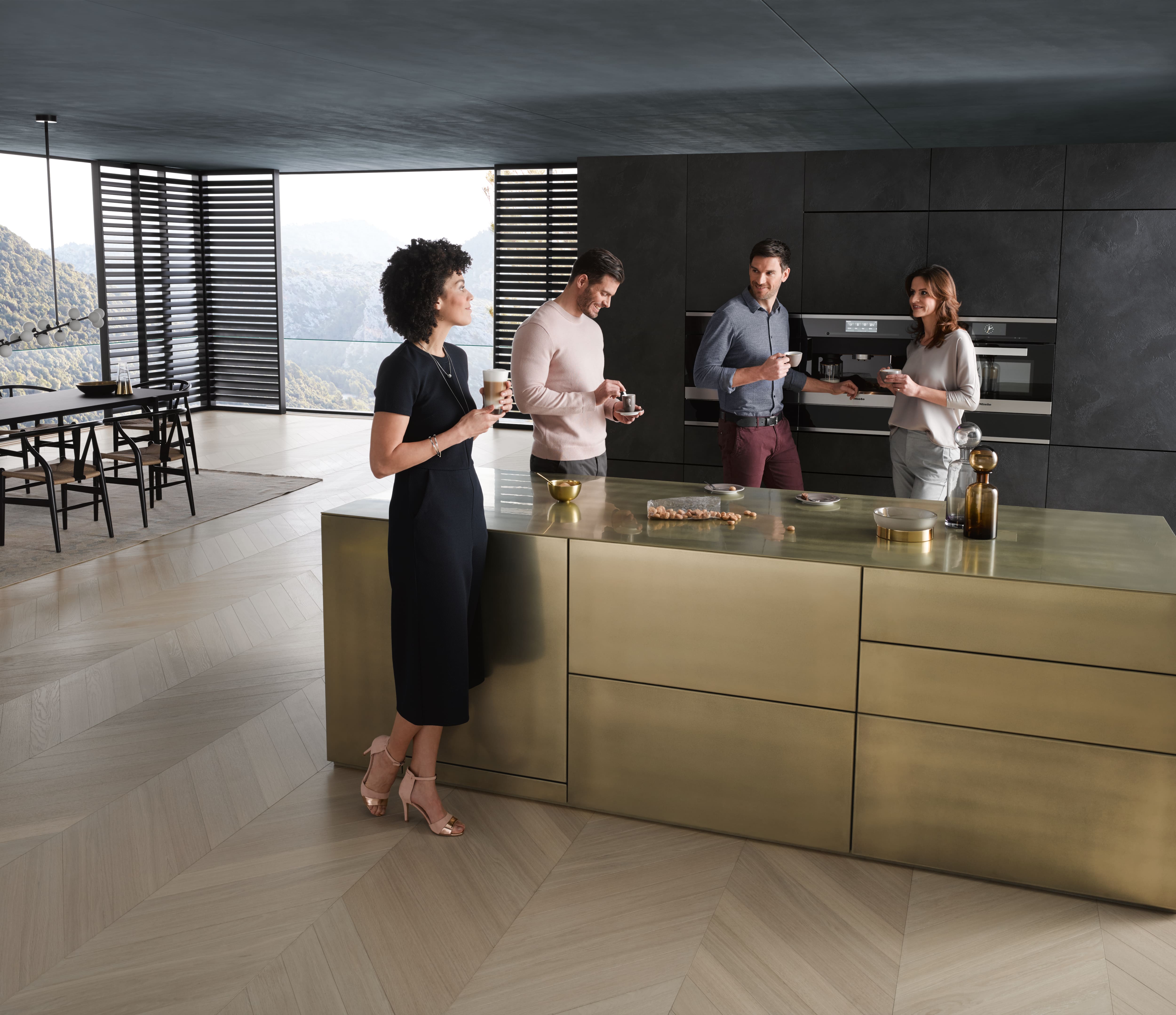 Grupa czterech osób robiących kawę w ekspresie do zabudowy Miele i miło spędzająca czas na rozmowie