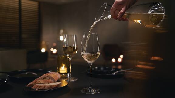 Romantikus hangulatban fehérbort öntenek egy borospohárba 