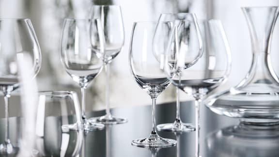 Clean, shining wine glasses on a reflective surface.