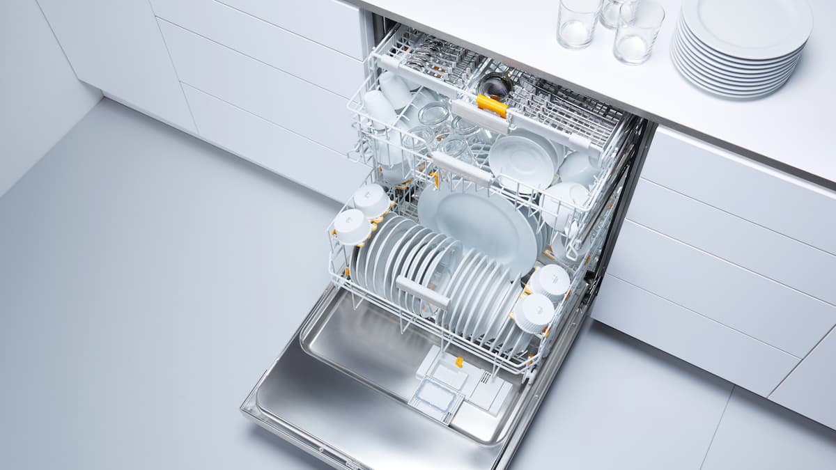 A throughput dishwasher, two tank dishwasher in a row on grey background. In front a further freshwater dishwasher with half-opened door.