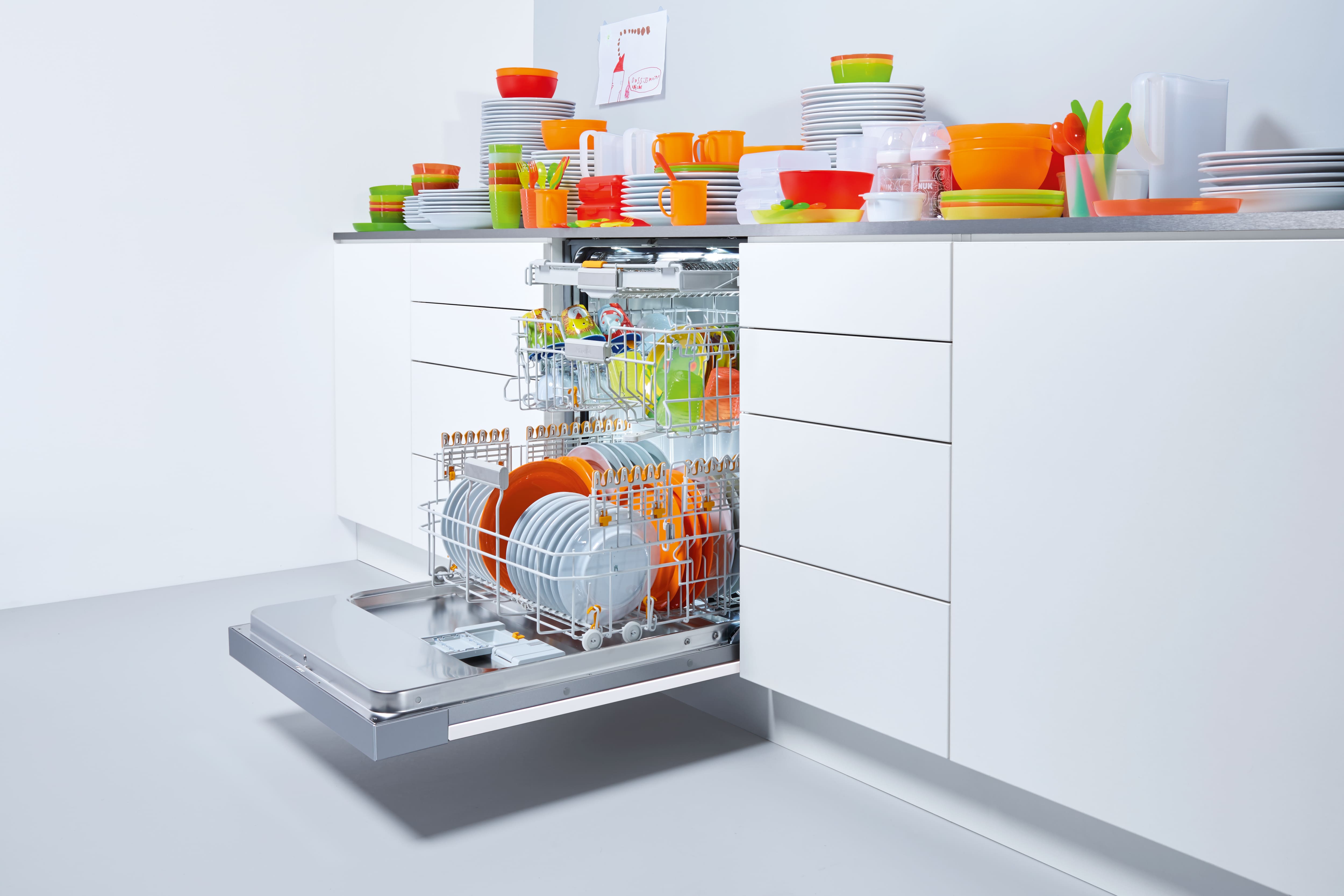 Lavavajillas abierto en la cocina con vajilla de colores.