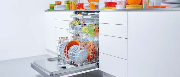 Öppen diskmaskin i köksskåp med färgglatt diskgods.