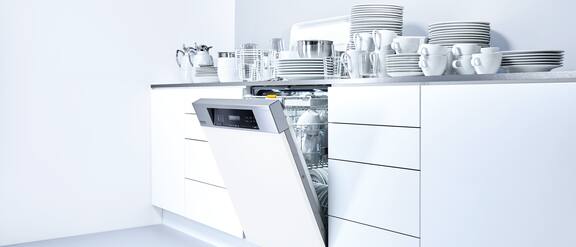 Nyitott Miele Profiline mosogatógép a konyhasarokban, tiszta edényekkel a munkafelületen.