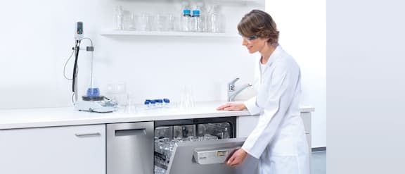La técnica de laboratorio abre el lavavajillas de laboratorio con la carga.