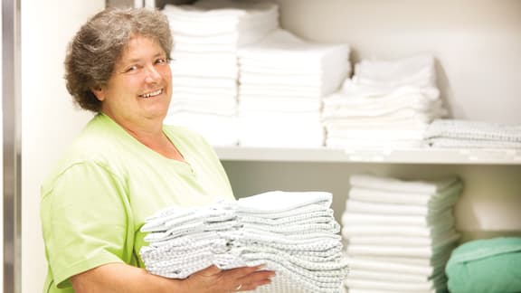Laundry manager storing clean linen in cupboard
