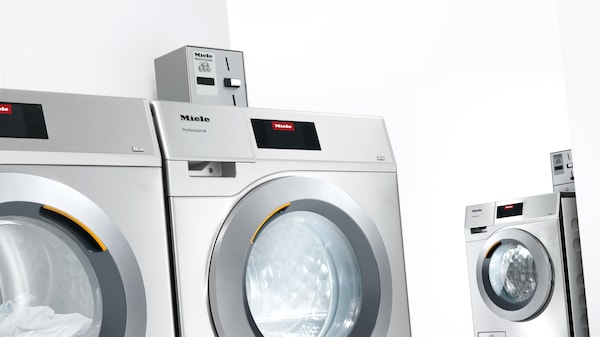 Waschmaschine und Trockner mit Kassiersystem im Waschraum.