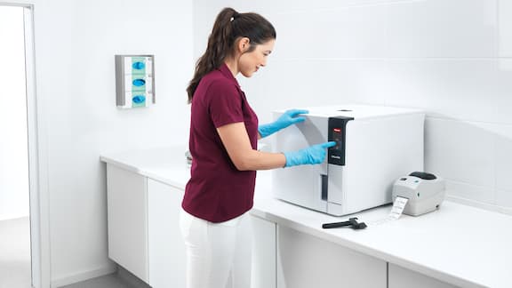 Une assistante médicale remplit un laveur-désinfecteur Miele Professional de table.