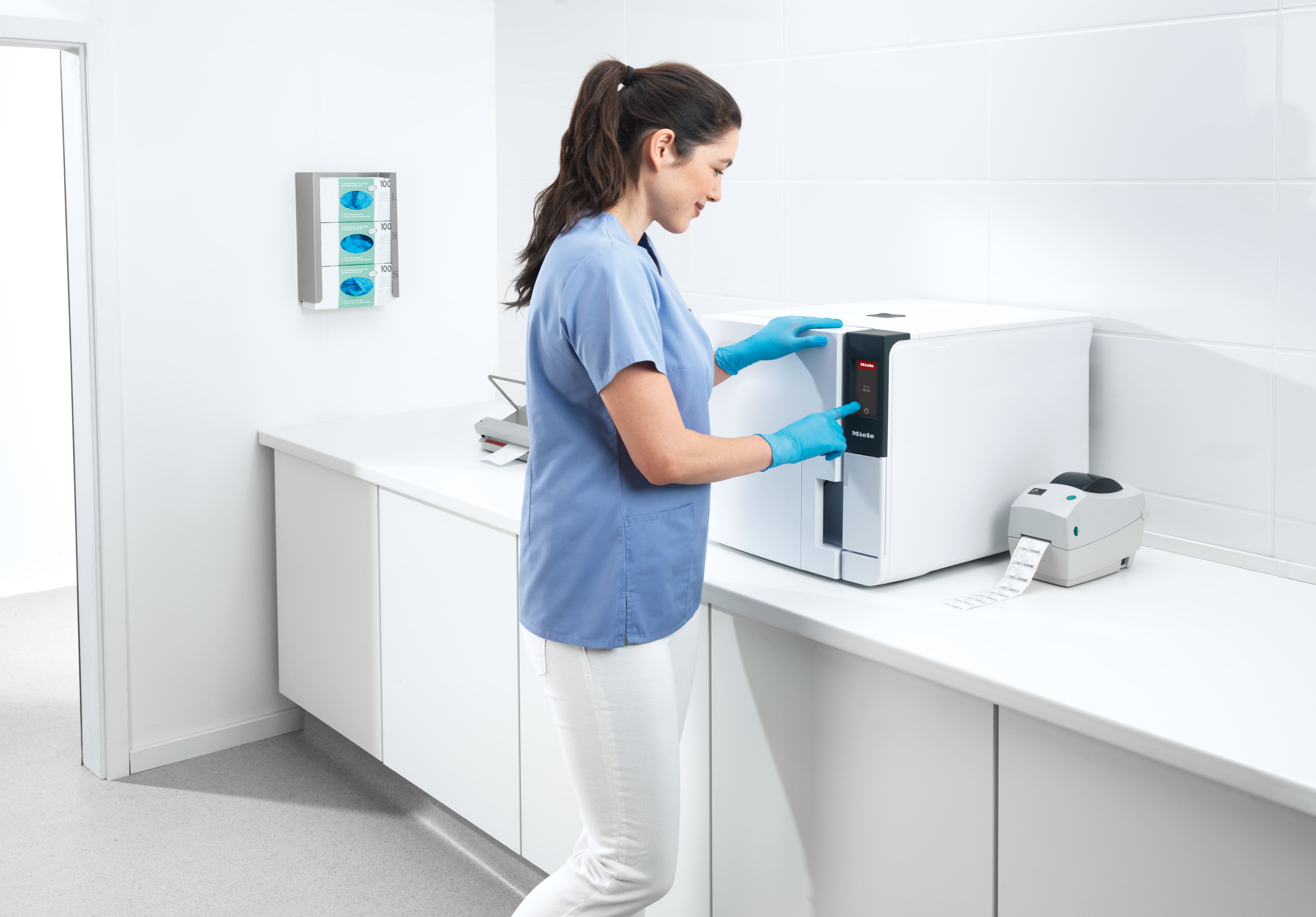 Zahnarzthelferin bedient Sterilisator im Aufbereitungsraum.