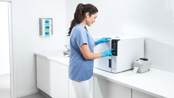 Une assistante médicale utilise un stérilisateur compact dans la salle de traitement.
