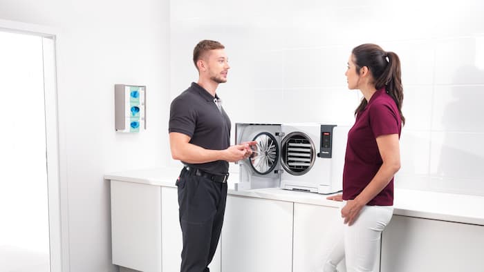 Collaborateurs de Miele conversant autour d’un stérilisateur compact.