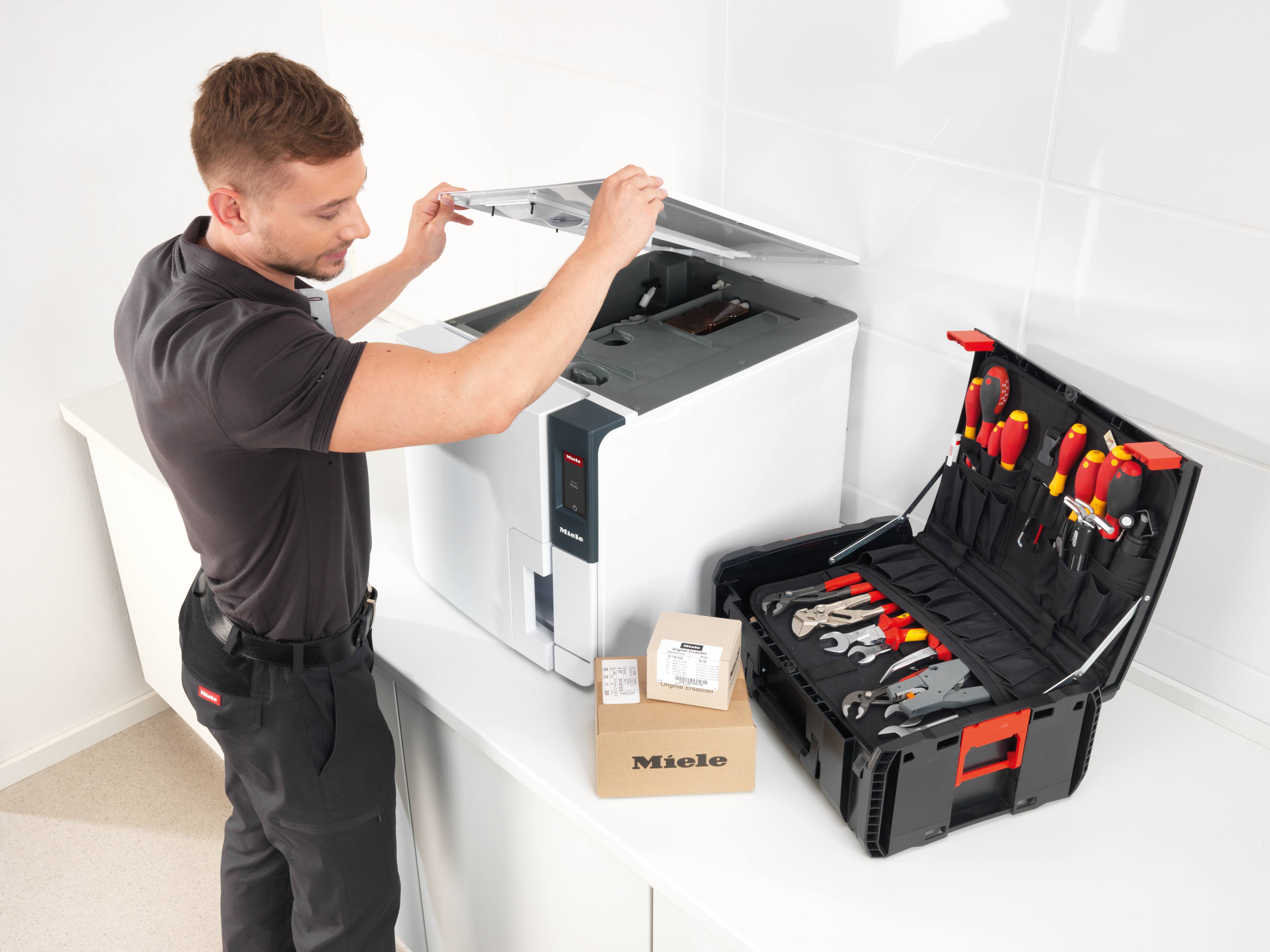 Servicetechniker hebt Deckel vom Klein-Sterilisator an.