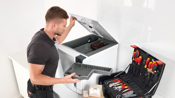 Técnico do serviço de assistência técnica da Miele Professional repara esterilizador de bancada com ferramenta da caixa de ferramentas