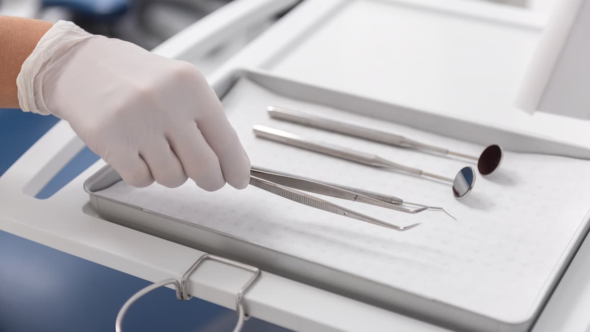 Hand with clinical glove holding dental tool