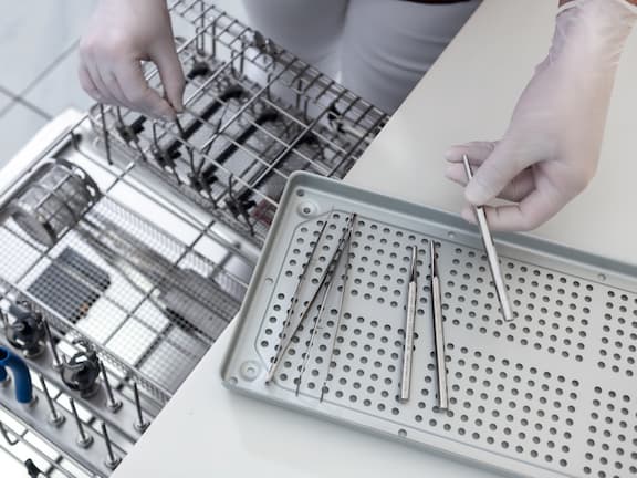 Close-up of hands clearing cleaned dental instruments onto tray