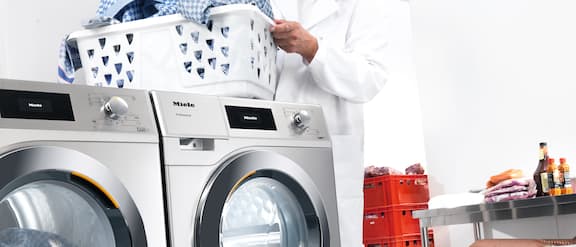 Slagterimedarbejder, der bærer en vasketøjskurv hen til vaskemaskinen.