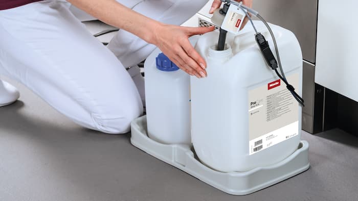 Canisters stand on a tray, dosing lance is inserted into canisters