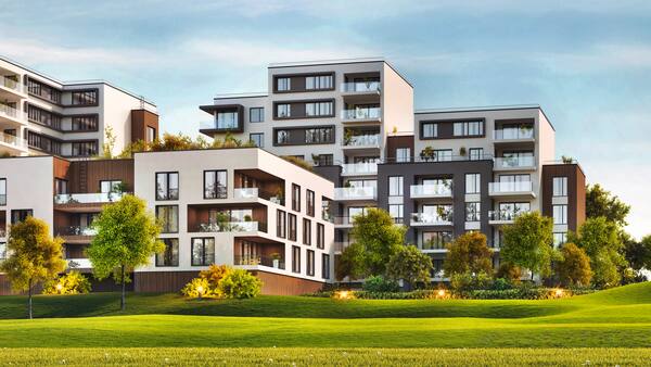 Moderner Wohnungskomplex mit grüner Wiese und blauem Himmel.