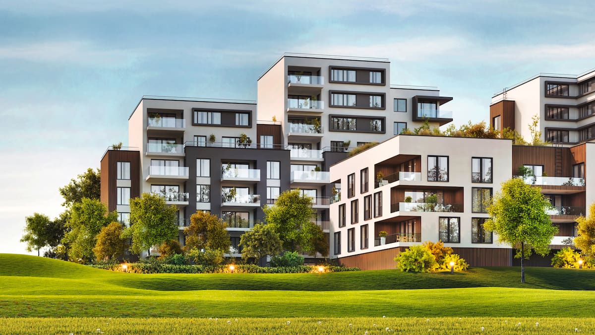 Several modern multi-family homes with green field and blue sky.