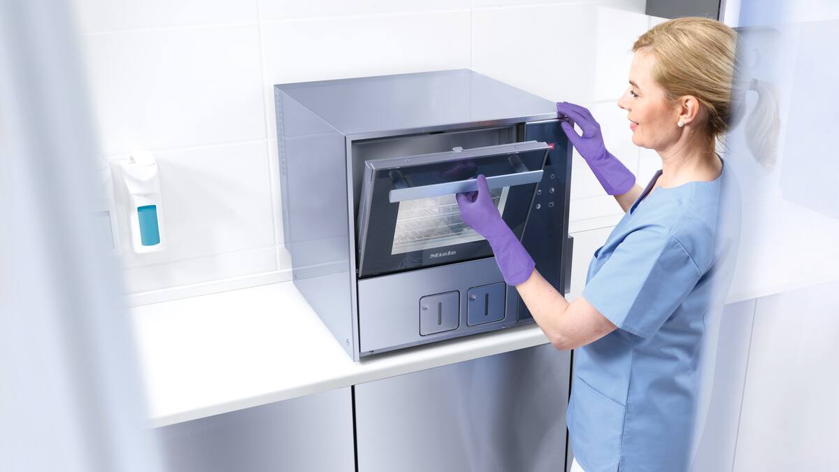 Un dentista usa una macchina per il lavaggio di strumenti dentali posata sul banco di una clinica
