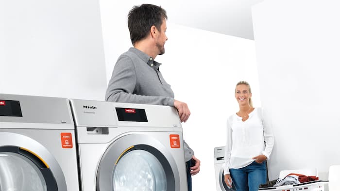 Due adulti chiacchierano in una lavanderia gestita con appWash.