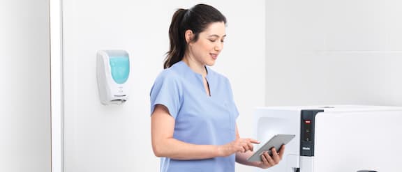 Eine Praxismitarbeiterin hält ein Tablet in den Händen.