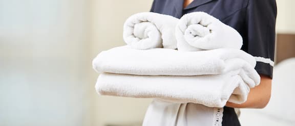 Medewerkster van een hotel draagt gevouwen handdoeken.