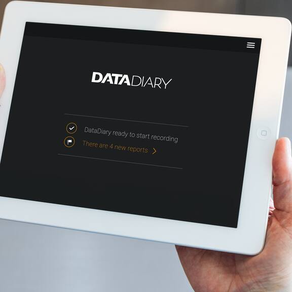 Hænder holder en tablet, hvor der står DataDiary på skærmen.