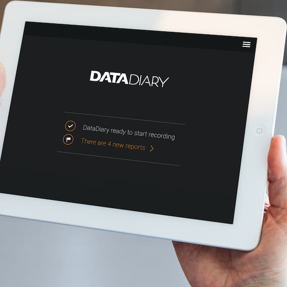 Hände halten ein Tablet, wo auf dem Bildschirm DataDiary zu lesen ist.