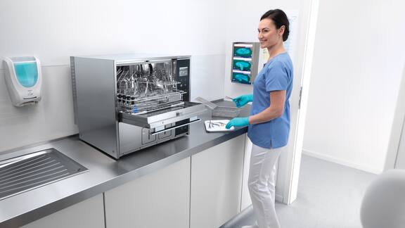 Un assistente carica una macchina speciale per il lavaggio e la disinfezione Miele Professional da banco.