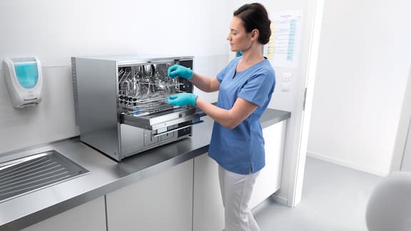 Zdravotní asistentka stojí u mycího a dezinfekčního automatu