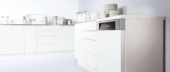 Lavastoviglie integrata in una fila di mobili cucina con stoviglie pulite.