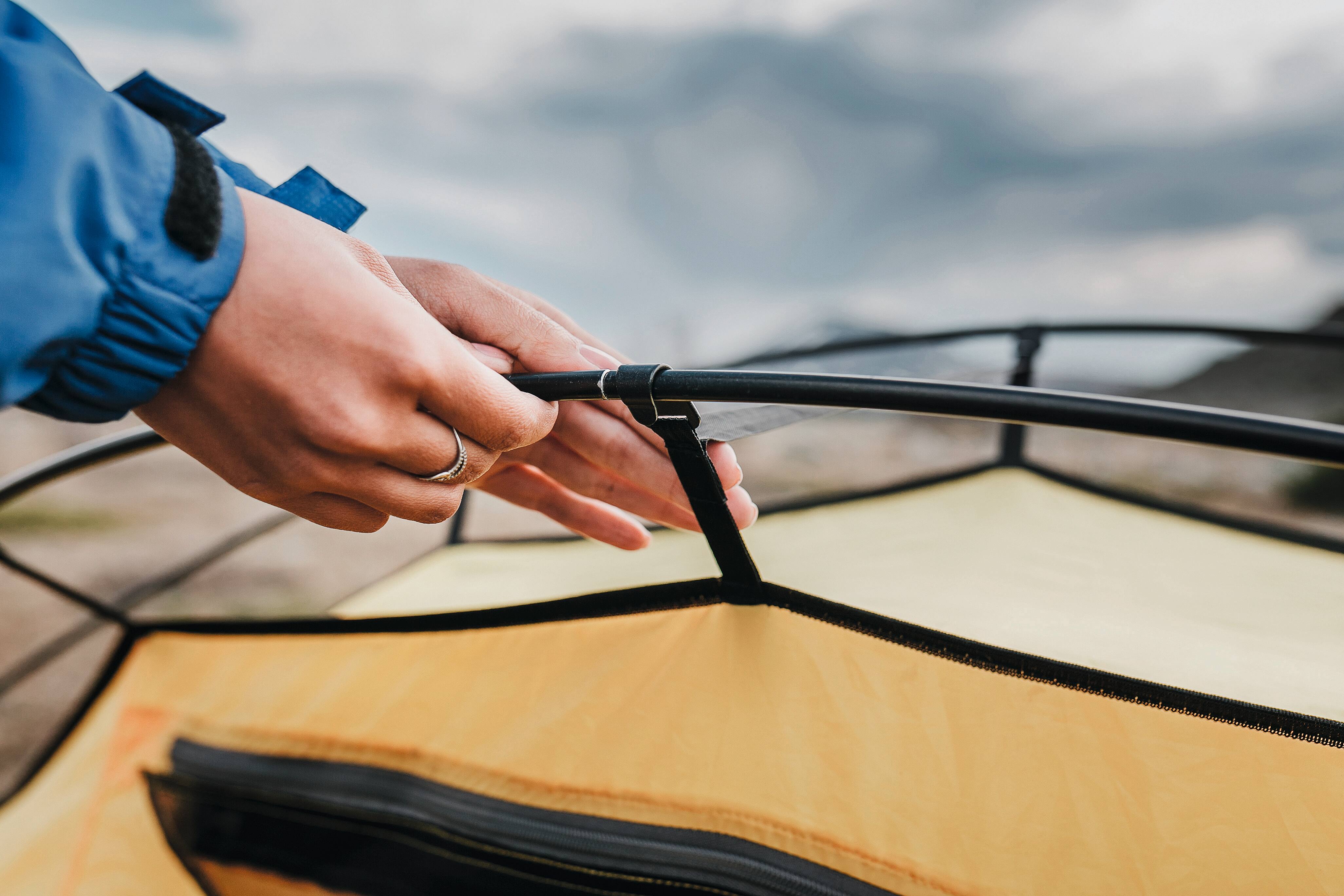 Hand richtet Zelt beim Campen.