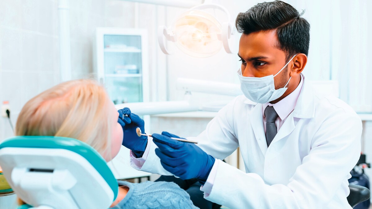 Zahnarzt mit Instrumenten untersucht Zähne einer Patientin.