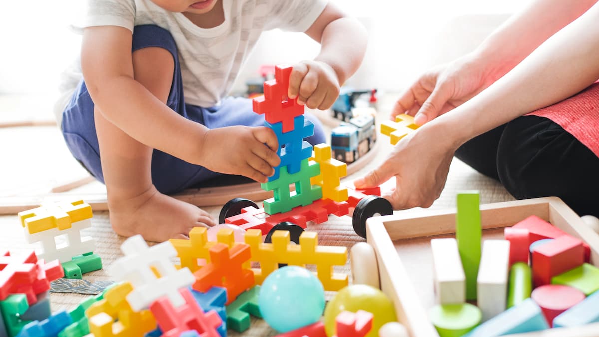 Twee handen spelen met kleurrijk speelgoed.