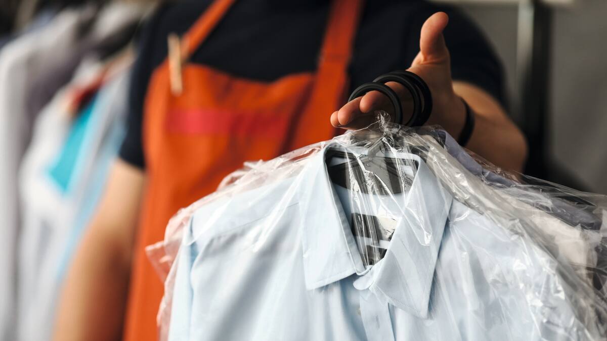 Käsi pitelee vastapestyjä, muoviin pakattuja paitoja