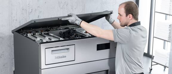 Servicetekniker åbner en Miele Professional-erhvervsvaskemaskine til vedligeholdelse