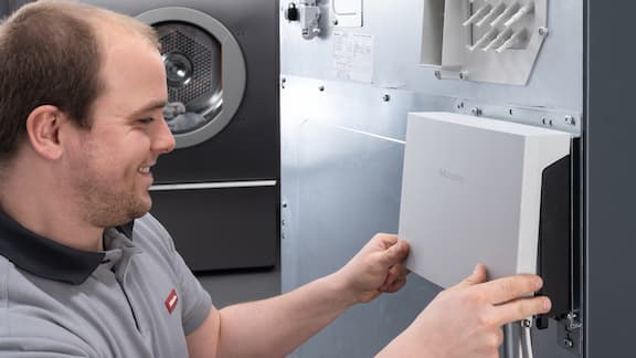 O técnico do serviço de assistência técnica da Miele repara a máquina de lavar roupa industrial