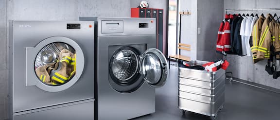 Máquina de lavar roupa e secador na lavandaria de um quartel de bombeiros.