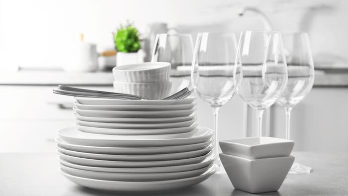 Close-up of a shiny clean crockery stack with glasses in the background