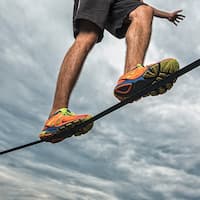 View from below of a slackliner balancing on a rope.