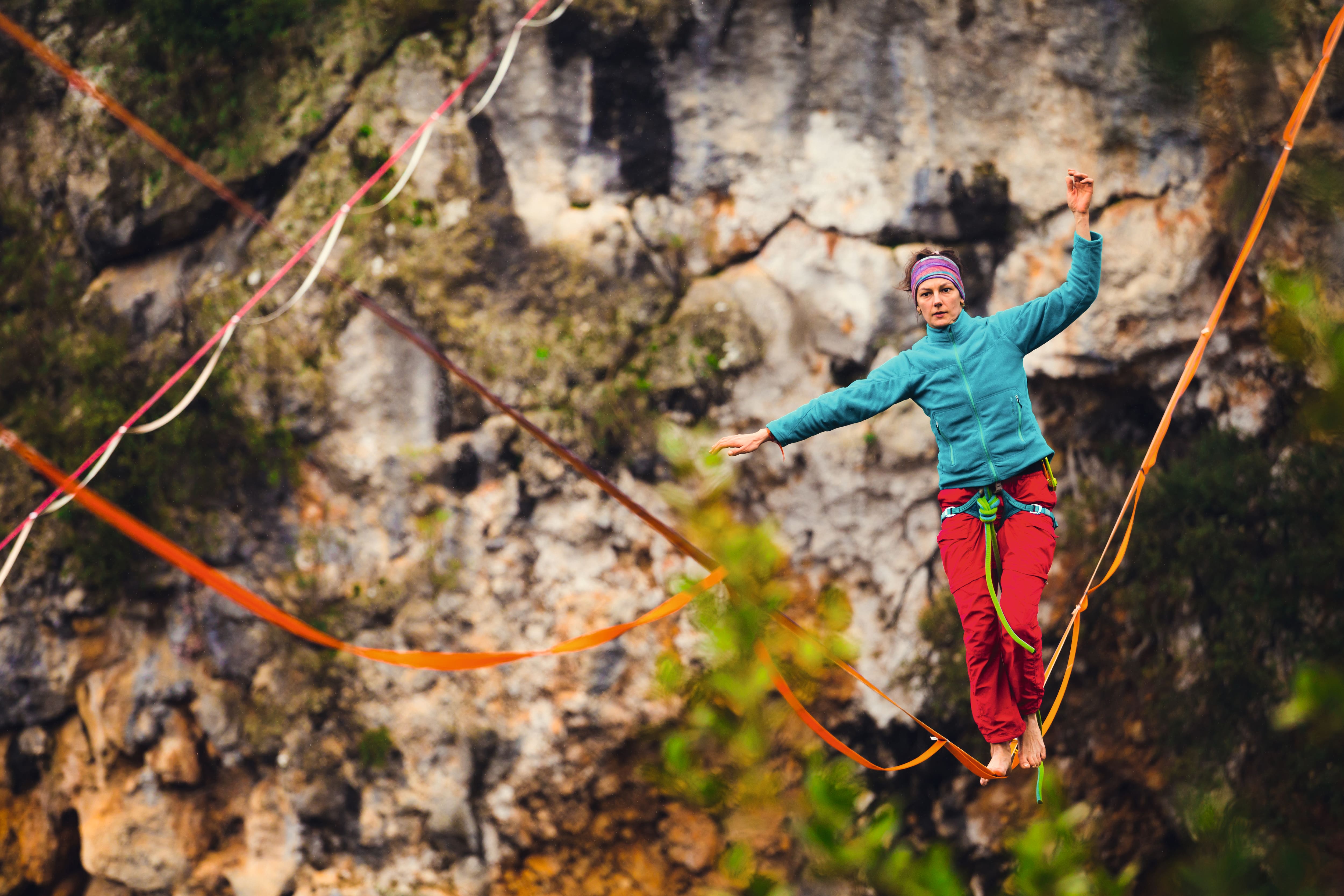 Eine Slacklinerin balanciert auf einem roten, durchhängenden Seil.