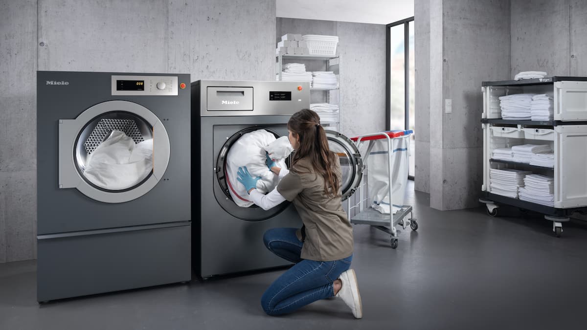 Una donna carica la lavatrice in una lavanderia
