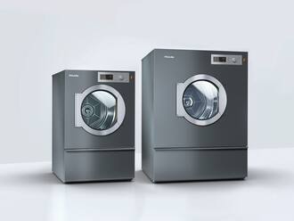 Two Miele tumble dryers stand in a white room