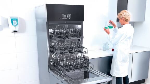 Una lavavetreria SlimLine aperta in un laboratorio, dove una collaboratrice ha dei campioni in mano.