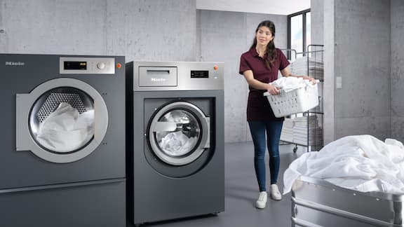 Una empleada satisfecha en la lavandería con un cesto de ropa.