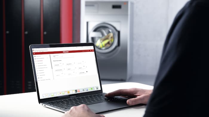 Man operating laptop in laundry room.