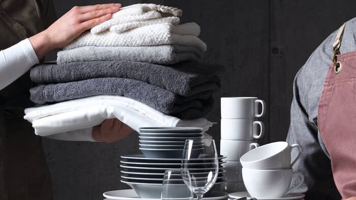 Gros plan sur 2 personnes tenant une pile de vaisselle et une pile de serviettes